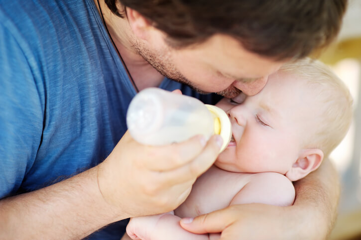 Far giver baby sutteflaske med modermælkserstatning